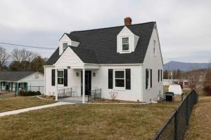 a white house with a black roof at All Seasons Cottage - Game Room - Firepit By Zen Living Short Term Rental in Luray