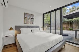 a bedroom with a large bed and a large window at Sophisticated 2-Bed by St Kilda Botanical Gardens in Melbourne