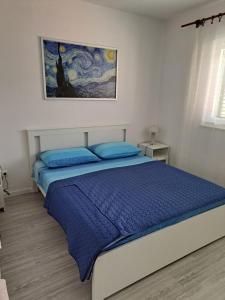 a bedroom with a bed with blue sheets and a painting at Apartments Big - free parking in Vodice