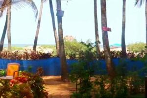 a view of a beach with palm trees and a chair at Samant Beach Resort in Malvan