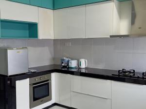 a kitchen with white cabinets and a black counter top at Ahnaf Homestay Desaru in Bandar Penawar