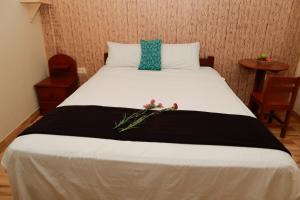 a bedroom with a large white bed with a flower arrangement on it at Irigoin Hospedaje in Nueva Cajamarca
