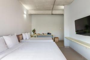 two beds in a white room with a tv at The Up Phu Quoc in Phu Quoc