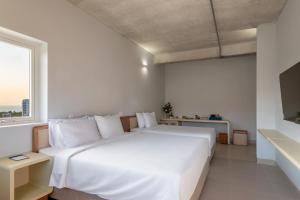 1 dormitorio con cama blanca y ventana en The Up Phu Quoc en Phu Quoc