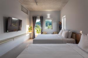 duas camas num quarto de hotel com uma janela em The Up Phu Quoc em Duong Dong