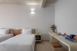 Habitación de hotel con 2 camas y escritorio en The Up Phu Quoc en Phu Quoc