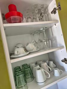 a cupboard filled with lots of cups and dishes at tzogias apartments helen in Argostoli