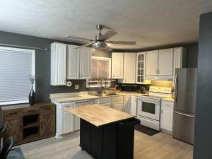 cocina con armarios blancos y ventilador de techo en Retreat to my Contemporary Home, en Morgantown