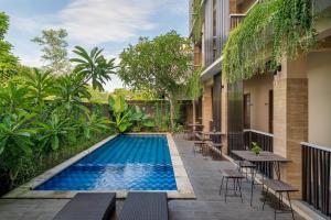 - une piscine avec des tables et des chaises à côté d'un bâtiment dans l'établissement Dream @ Jimbaran, à Jimbaran