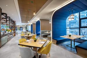 een restaurant met blauwe muren en tafels en gele stoelen bij voco Xian ETDZ, an IHG Hotel in Xi'an