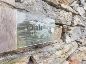 een teken aan de zijkant van een stenen muur bij Oak Cottage in Ulverston