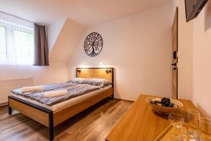 1 dormitorio con cama y mesa de madera en Penzion Kormorán, en Vranov nad Dyjí