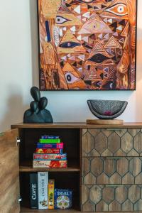 a painting on a wall above a book shelf with books at Eucalyptus Apartment Corfu Town - Starlink in Anemómylos