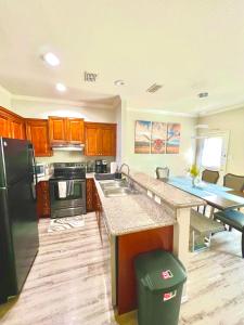 a kitchen with wooden cabinets and a black refrigerator at A Blissful Townhome with a Game Room Near AT&T Stadium, Six Flags, DFW Airport in Arlington