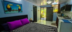 1 dormitorio con 1 cama grande con almohadas moradas en Cabina Azul in Bejuco Beach with queen bed but no air conditioning, en Bejuco