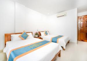 Duas camas num quarto com paredes brancas em Mặt Trời Tím Hotel & Spa em Da Nang