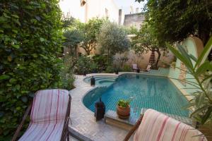 a swimming pool with two chairs next to it at Riad Norma in Fès