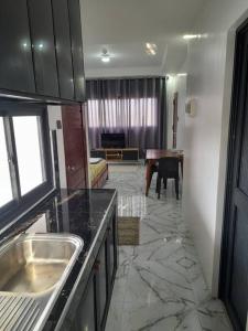 uma cozinha com um lavatório e uma sala de estar com uma mesa em Pozorrubio Apartment em Pozorrubio