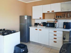 a kitchen with white cabinets and a stainless steel refrigerator at Dawson's Creek in Cape Town