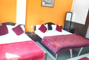 Cette chambre comprend 2 lits avec des oreillers rouges et blancs. dans l'établissement GRG Ashiyana Palace Parade Kothi Road Varanasi, à Varanasi