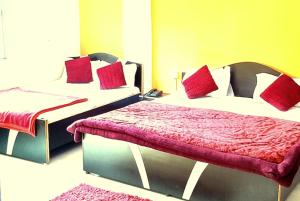 two beds with red pillows in a room at GRG Ashiyana Palace Parade Kothi Road Varanasi in Varanasi