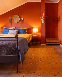 a bedroom with orange walls and a bed with blue pillows at Cozy Main Square Apartment in Pristina