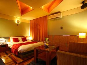鳥栖市にあるHOTEL Villamure ogoriのベッドとソファ付きのホテルルーム
