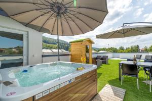 bañera de hidromasaje en un patio con sombrilla en Rooftop Home With Whirlpool & Sauna en Trebnje