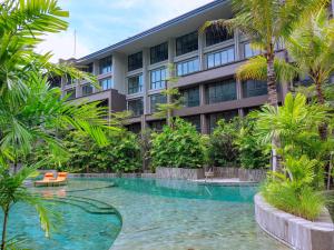 a hotel with a swimming pool in front of a building at Pearl Nusa Dua Suite in Nusa Dua