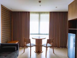 a living room with a table and chairs and a window at Pearl Nusa Dua Suite in Nusa Dua