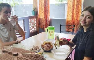 Un uomo e una donna seduti a tavola mangiando cibo di Enoch Guest House a Mannar
