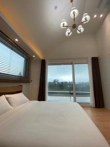 a bedroom with a large bed and a large window at Opera Garden in Seogwipo