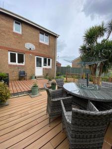 eine Terrasse mit einem Tisch und Stühlen auf einer Holzterrasse in der Unterkunft ROSE COTTAGE in Ryde