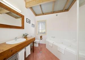 een badkamer met een wastafel, een bad en een toilet bij North Lodge Clan Cottage in Pokolbin +9 foto's