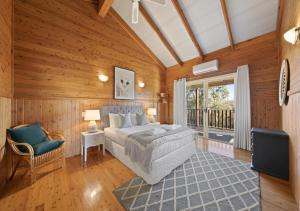 a bedroom with a bed and a chair and a window at North Lodge Clan Cottage in Pokolbin