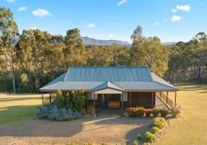 a house with a tin roof on a field at North Lodge Clan Cottage in Pokolbin