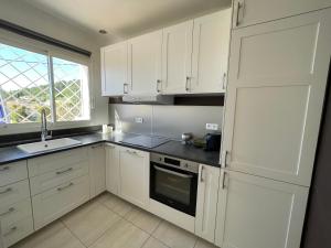 cocina con armarios blancos, fregadero y ventana en Maison à la Naronne en Bandol