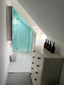 baño con ducha y tocador con botellas. en Billie's seaside retreat, en Lyme Regis