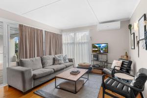 a living room with a couch and a table at Sunseeker Cottage - Mangawhai Heads Holiday Home in Mangawhai