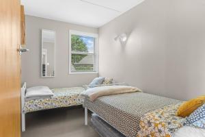 een slaapkamer met 2 bedden en een spiegel bij Sunseeker Cottage - Mangawhai Heads Holiday Home in Mangawhai