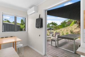 a living room with a sliding glass door to a patio at Pearl's Embrace - Mangawhai Heads Studio in Mangawhai