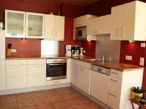 a kitchen with white cabinets and red walls at Spacious Chalet in Piesendorf with Sauna in Dürnberg