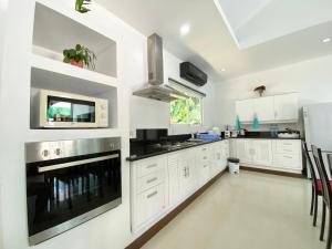 a kitchen with white cabinets and black appliances at Chalong - 4 Bedroom Private Pool Villa - Phuket in Chalong