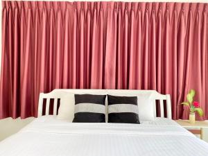 a bed with two pillows in front of a red curtain at Phikun 4 BR Private Pool Villa in Chalong 