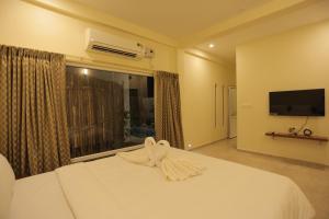 a bedroom with a white bed and a large window at PALM PARADISE Beach Resort in Puducherry