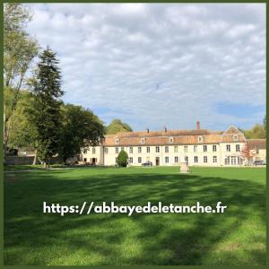 un gran edificio con un gran campo de césped delante de él en Abbaye de l'Etanche -1 chambre d'hôtes - Un cadre naturel exceptionnel - 