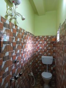 ein Bad mit einem WC und einer Fliesenwand in der Unterkunft ATITHYA GUEST HOUSE in Srī Niketan