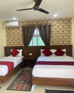 a bedroom with two beds and a window at Hotel Safari Suite in Sauraha