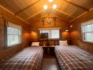 a bedroom with two beds in a wooden cabin at FOLKWOOD VILLAGE八ヶ岳 in Iwa-kubo