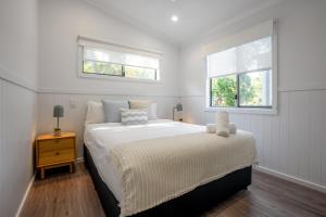 a white bedroom with a large bed and two windows at BIG4 Tasman Holiday Parks - Nambucca Heads in Nambucca Heads